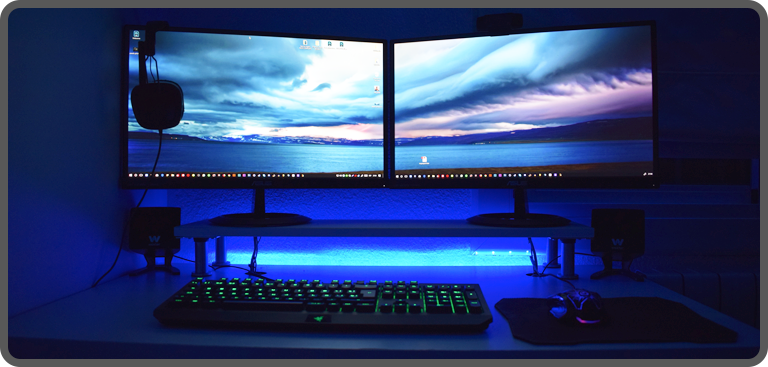 A pro gamer spec desktop PC set up with dual monitor display, headset, gaming keyboard and mouse