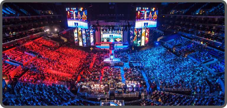 An audience of gaming fans watch a live esports event in a stadium arena